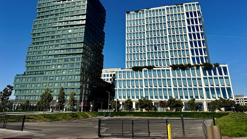 Two hands passing a plain brown folder across a table, with a coffee cup and notepad at the edge of the frame.