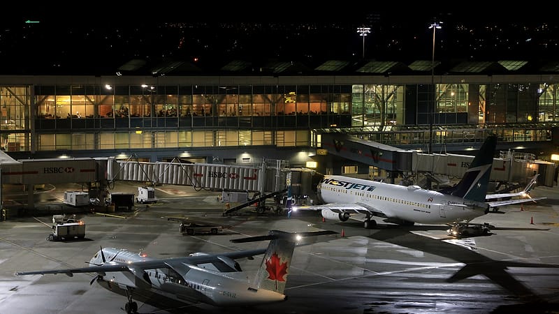 A row of closed passport control booths at an international airport with roller shutters lowered over the counters.