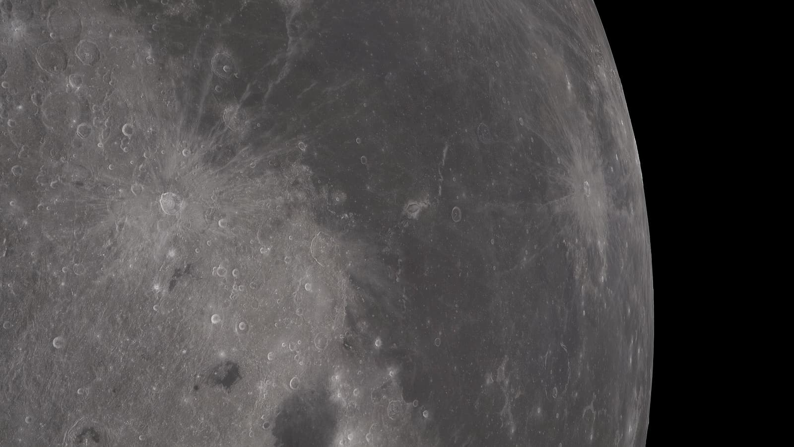 A gray cratered rock surface photographed at low angle with long shadows and fine dust covering scattered stones.