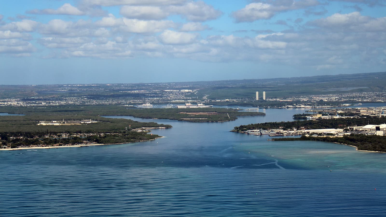 A small island airport apron at midday with a parked turboprop, palm trees, and low terminal buildings.