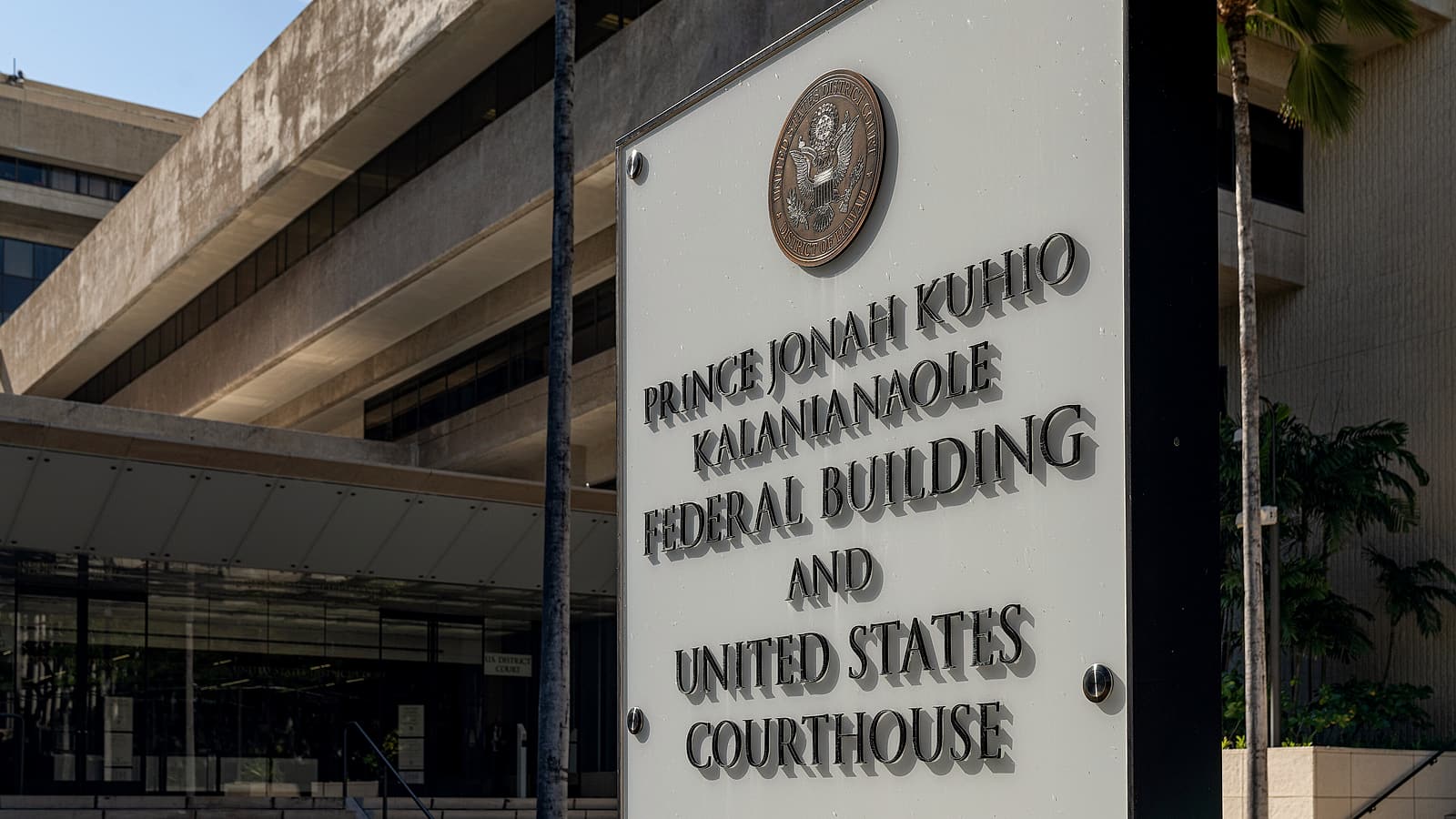 The stone facade of a federal courthouse with tall columns and a row of doors, photographed from the steps below.